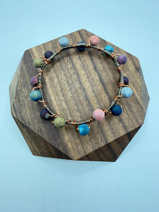 Colorful beaded bracelet on a wooden stand with a light blue background