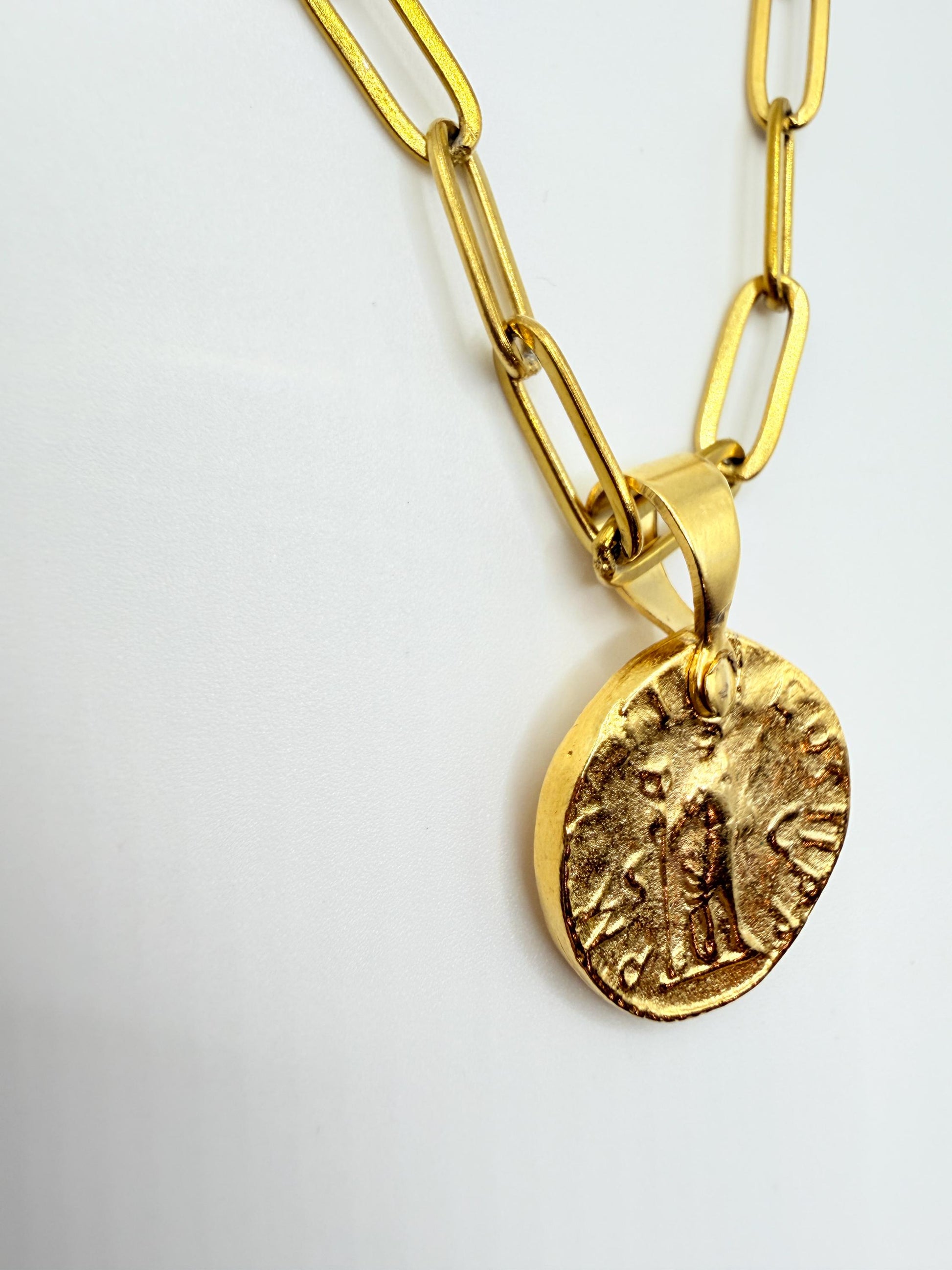 Gold necklace with a coin pendant on a white background