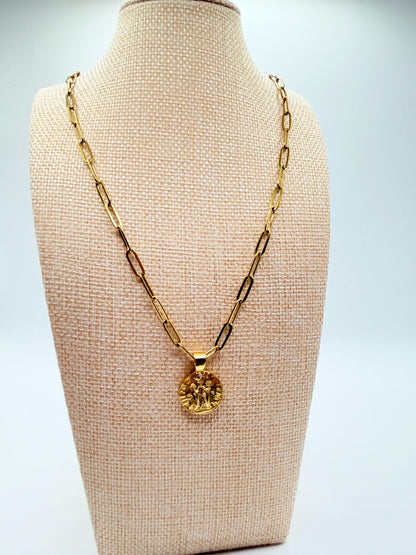 Gold necklace with a pendant on a beige mannequin bust against a light gray background