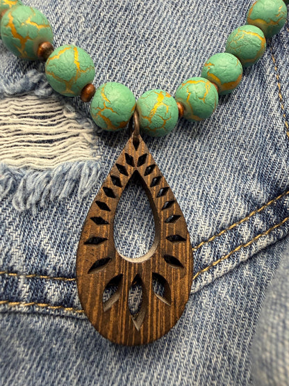 Necklace with turquoise beads and a wooden pendant on denim fabric