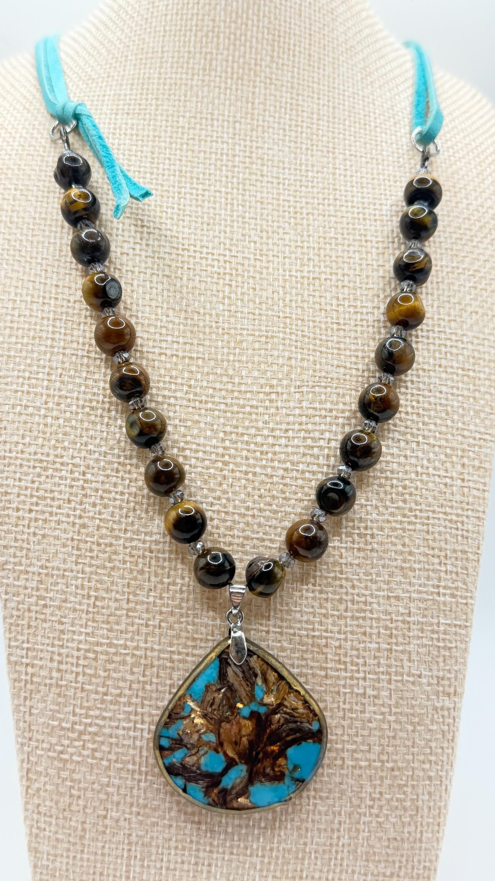 Necklace with beads and a turquoise pendant on a mannequin bust.