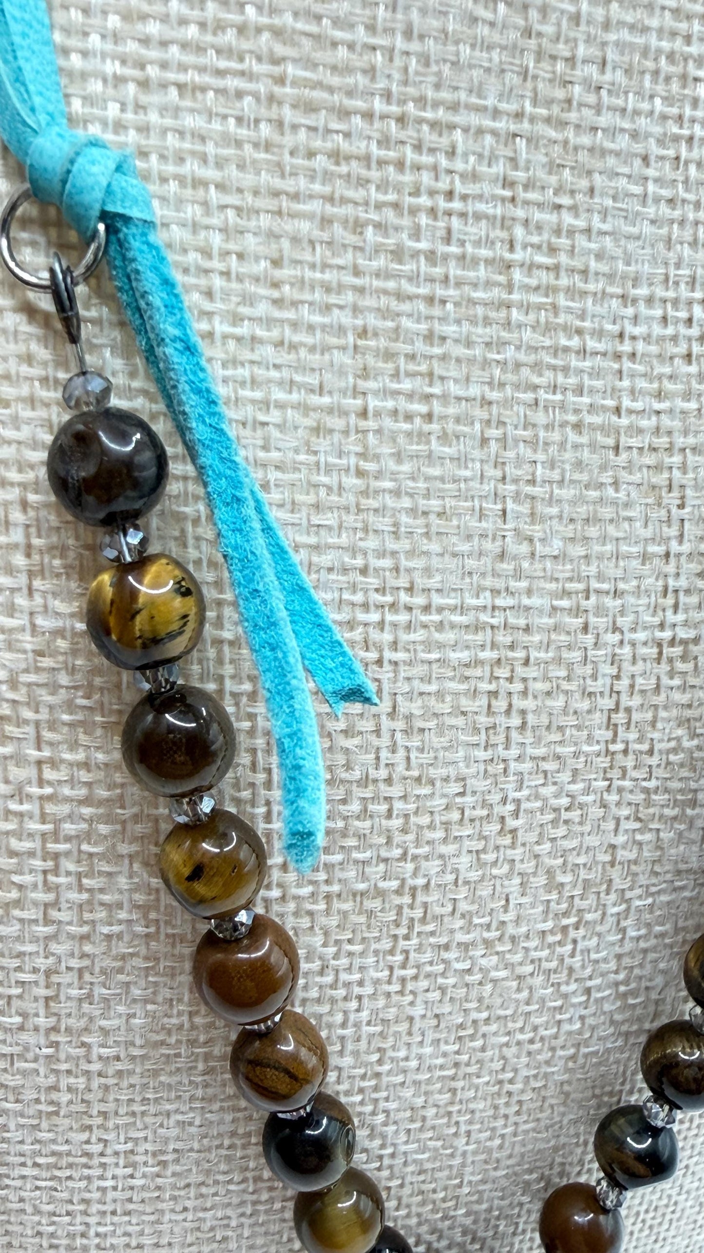 Beaded necklace with turquoise cord on a textured beige background