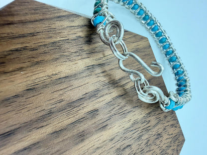 Silver bracelet with turquoise stones on a wooden surface