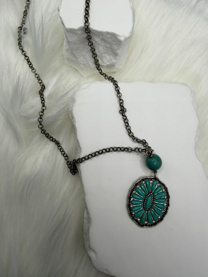 Necklace with a turquoise pendant on a white mannequin arm against a white background