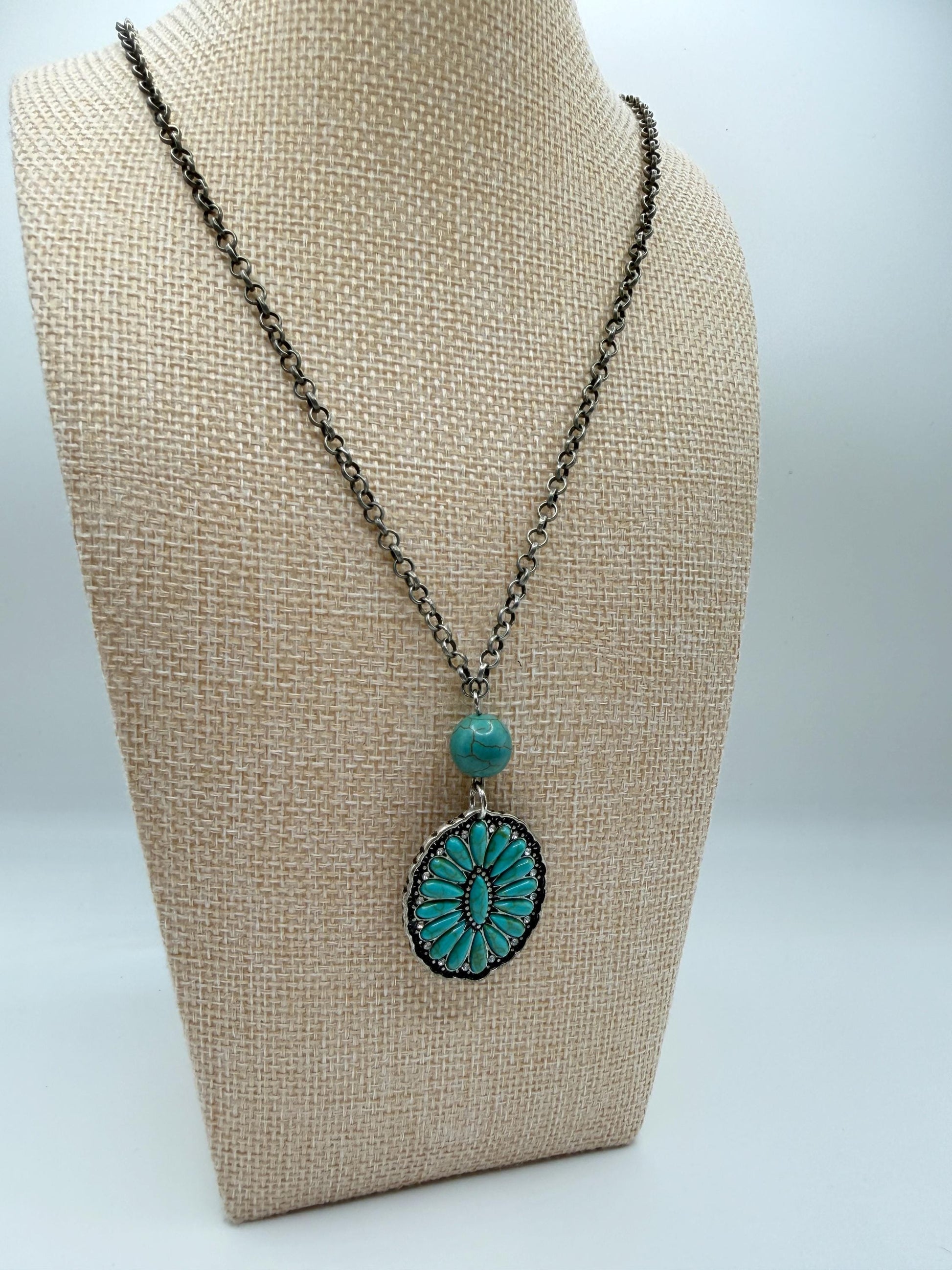 Necklace with turquoise pendant on a beige bust against a white background