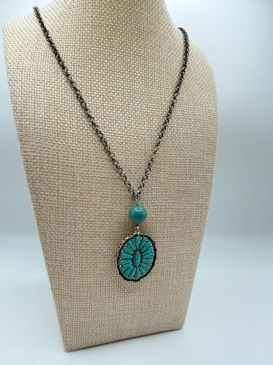 Necklace with turquoise pendant on a beige bust against a white background