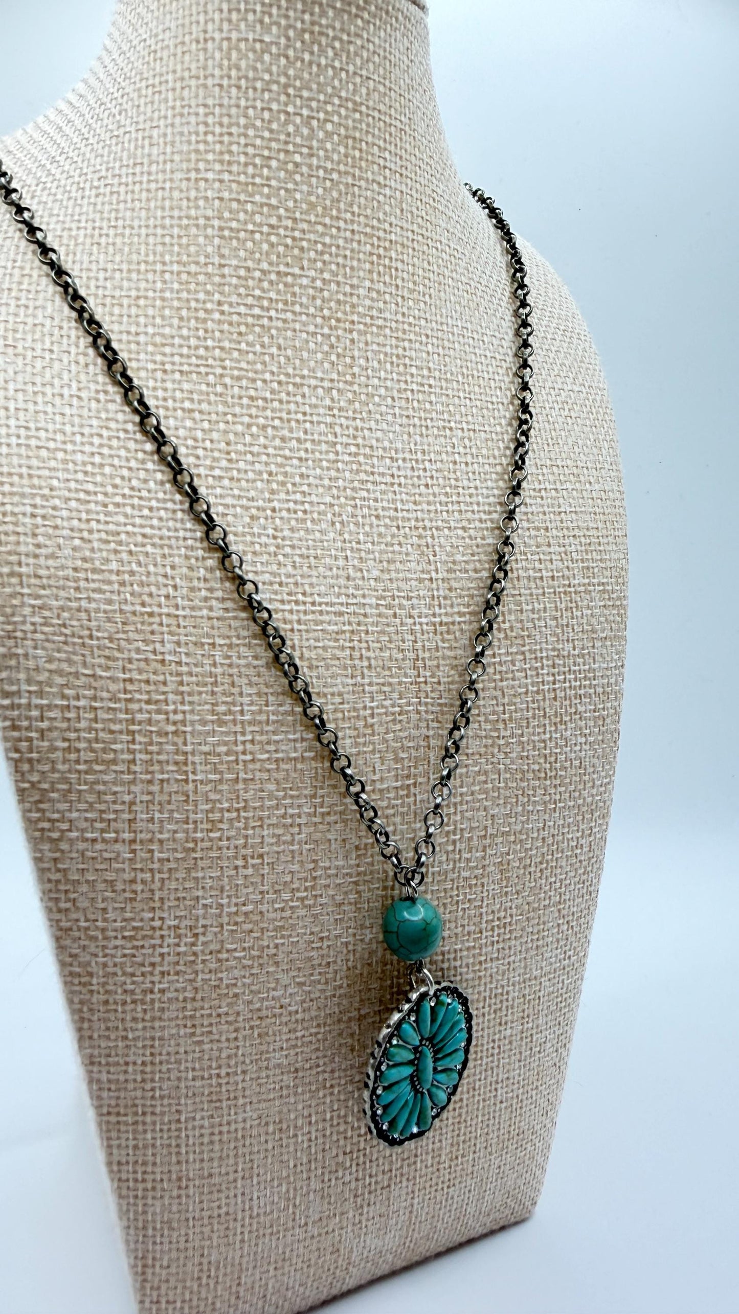Necklace with a turquoise pendant on a mannequin bust against a light background