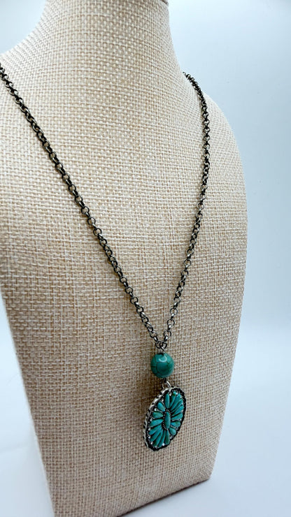 Necklace with a turquoise pendant on a mannequin bust against a light background