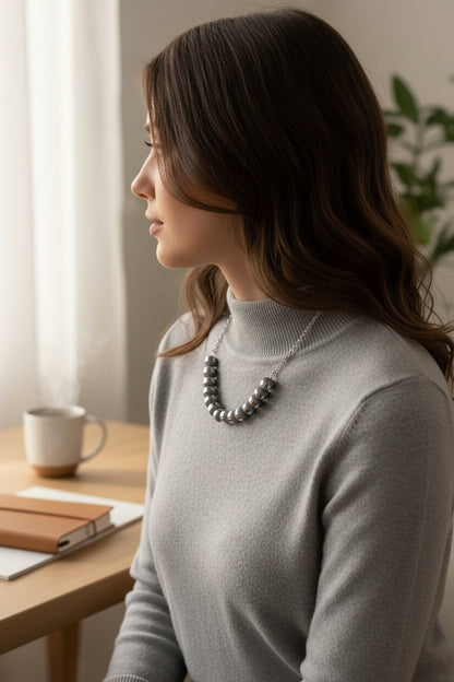 Woman sitting at a desk with a cup and notebook, wearing a gray turtleneck sweater.