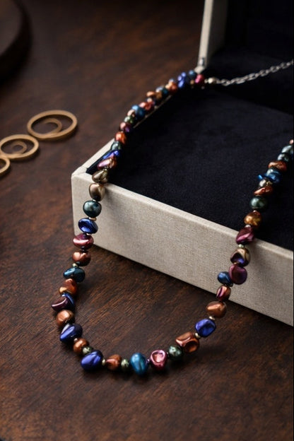 Multicolored pearl necklace on a wooden surface with a box in the background